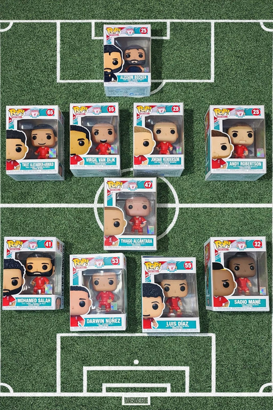Liverpool FC Funko Pop collection featuring Mohamed Salah, Jordan Henderson, Darwin Núñez, Luis Díaz, Sadio Mané, Thiago Alcântara, Trent Alexander-Arnold, Virgil van Dijk, Andy Robertson, and Alisson Becker arranged in a football formation on a grass pitch with field markings.
